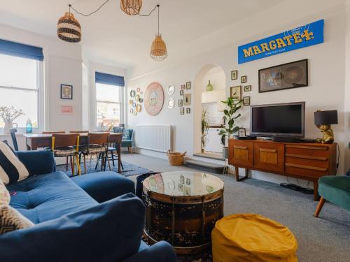 a living room with a blue couch and a tv at The Lynton Lookout in Margate