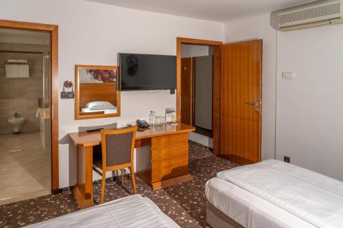 a hotel room with a desk and a bed and a bedroom at Hotel Piramida in Maribor