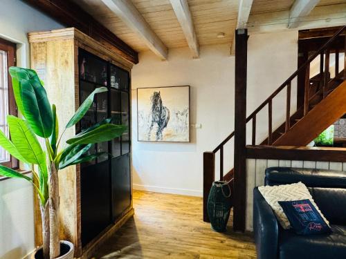 a living room with a staircase and a plant at La Maison Rouge Au coeur de la ville. in Riquewihr