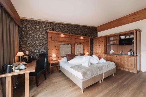 a bedroom with a large bed and a desk and a desk at Wellness Aparthotel Panorama Alpin - Ferienwohnungen Jerzens im Pitztal in Jerzens