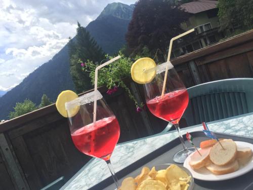 two glasses of red wine on a table with food at Hotel Tosa in Madonna di Campiglio