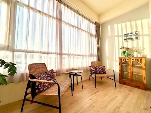 a living room with chairs and a table and a large window at 日月慢遊 in Yuchi