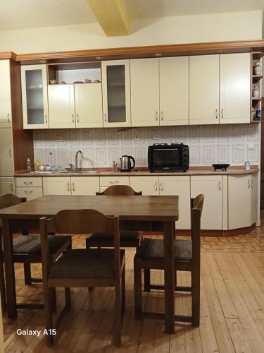 a kitchen with a wooden table and white cabinets at BAHAR Apartment-Ohrid in Ohrid