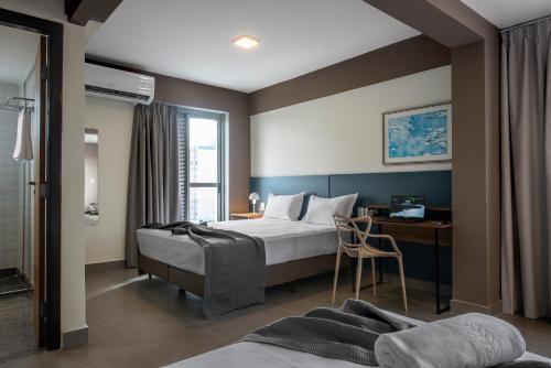 a bedroom with a bed and a desk with a chair at Lym Flat Hotel in Uberlândia