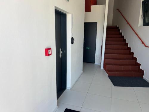 a hallway with stairs and a door with a red box at KOREK Mikulov apartmán in Mikulov