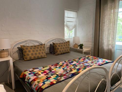 a bedroom with a bed with a colorful quilt on it at Die Kuierhuis - style in the heart of Stanford in Stanford