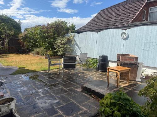 a stone patio with a grill and a table at The RS Inn Cozy Homestay Premium Private Rooms With Parking Near Birmingham Airport, Lake Park For Solo, Couples & Family in Kingshurst