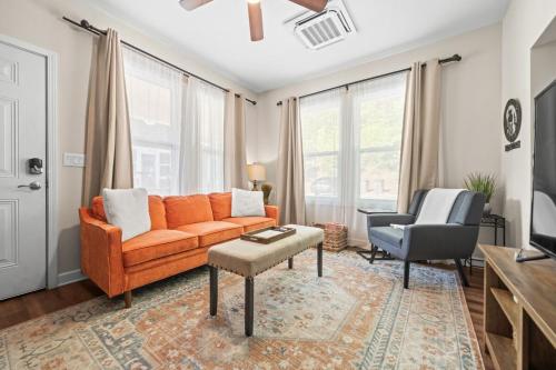 a living room with an orange couch and a chair at Mountain Bungalow-Walk to Downtown/Biker's Dream! in Hot Springs