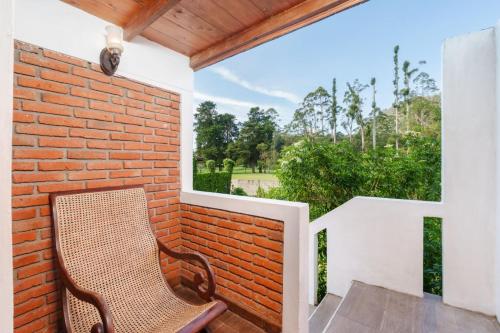 a chair sitting on a balcony with a brick wall at The Golf Green City Bungalow in Nuwara Eliya