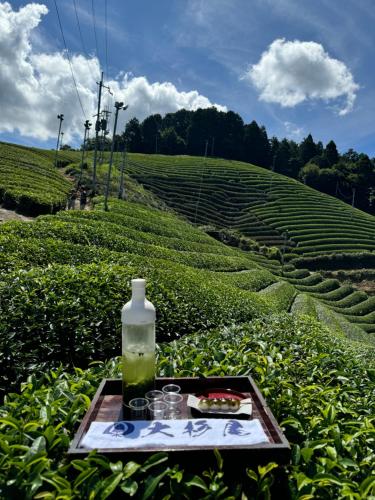 a table with a bottle and glasses on a tray in a field at Osugi-ya 大杉屋 in Wazuka