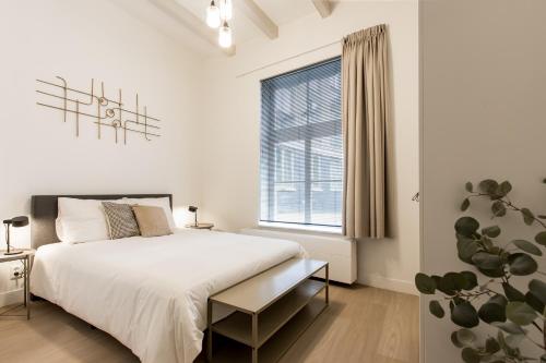 a white bedroom with a bed and a window at City Apartments Nijmegen in Nijmegen