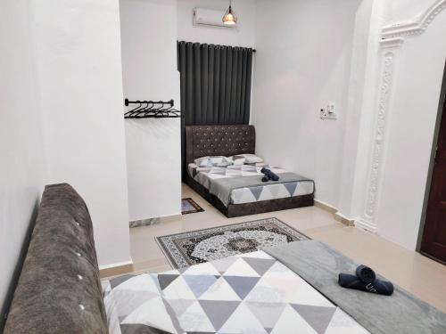 two beds in a room with a couch and a rug at Roomstay Kak Ton DELUXE ROOM in Kuala Terengganu