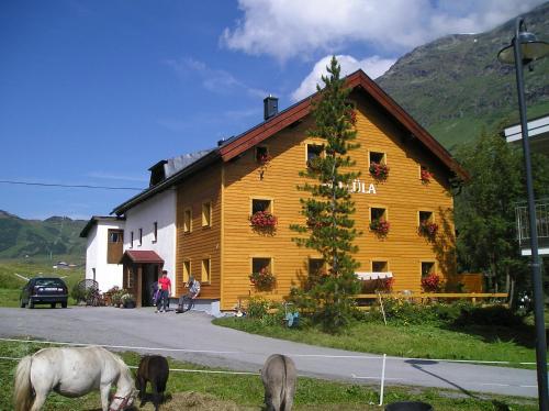 ガルチュールにあるPension Vallülaの目の前に馬の放牧がある大きな木造建築