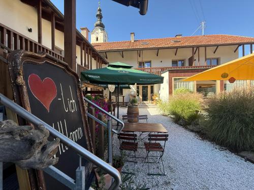 a patio with a table and a green umbrella at Landgasthof Sagenhaft in Klagenfurt