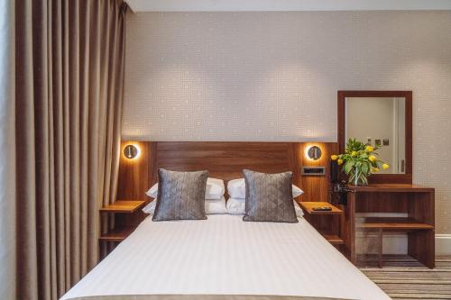 a bedroom with a large white bed and a mirror at London House Hotel in London
