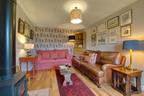 a living room with a leather couch and a pink couch at The Stables in Thurgarton