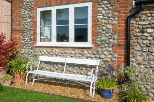 a white bench in front of a building with a window at The Stables in Thurgarton