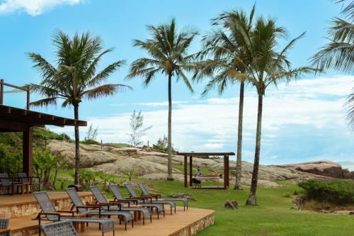 a row of chairs and palm trees at a resort at Hotel Atalaia do Mariscal in Bombinhas