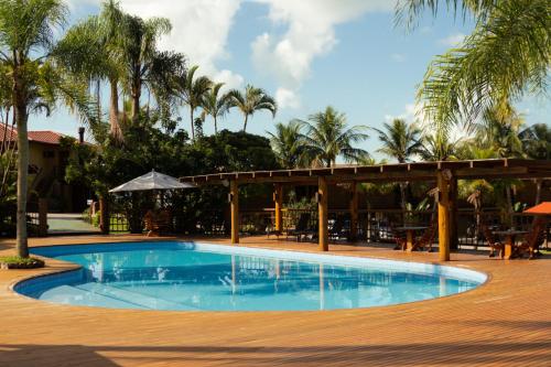 a swimming pool with a pavilion and palm trees at Hotel Atalaia do Mariscal in Bombinhas