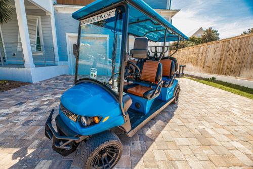 un carrito de golf estacionado frente a una casa en Blue Horizon Golf Cart Pool & Sleeps 32, en Santa Rosa Beach
