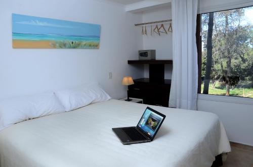 a laptop computer sitting on top of a bed at Jaina Resort & Spa in Mar de las Pampas