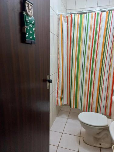 a bathroom with a shower curtain and a toilet at Chácara with pool and trails in the Cerrado biome in São Carlos