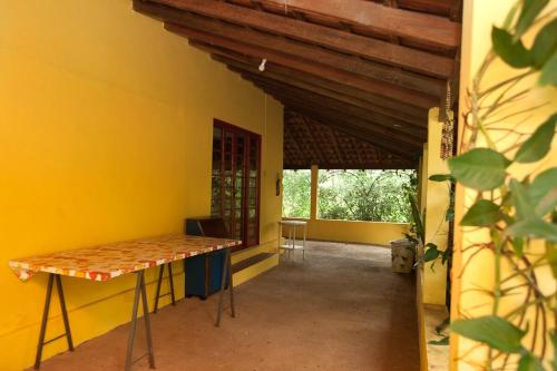 a room with a table and a yellow wall at Chácara with pool and trails in the Cerrado biome in São Carlos