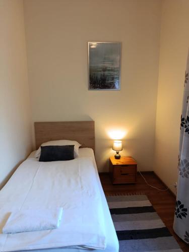 a small bedroom with a white bed and a lamp at Swojski Klimat in Płońsk