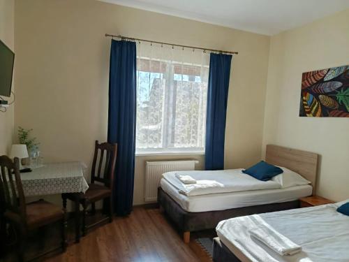 a room with two beds and a table and a window at Swojski Klimat in Płońsk