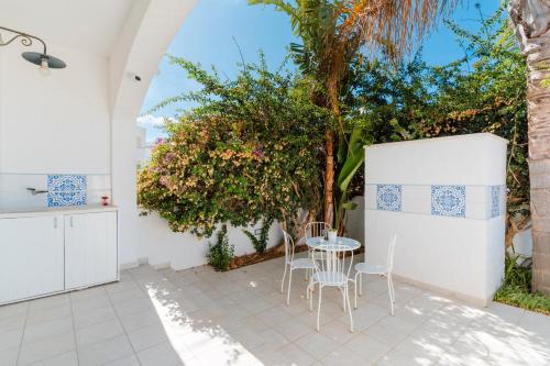 a patio with a table and chairs and trees at Il Rosmarino Casa Vacanze in Taviano