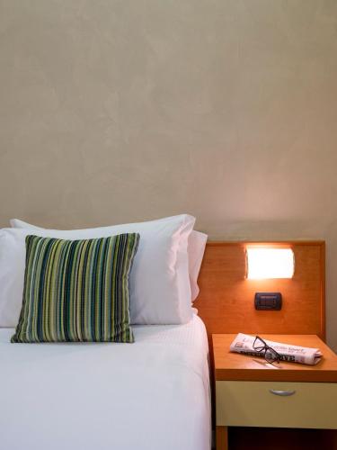 a bed with a pillow and a table with a lamp at Hotel Embassy in Pero