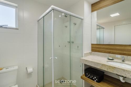 a bathroom with a glass shower and a sink at Estadia com piscina e sauna a poucos passos da praia em Cabo Frio - HSC in Škorak