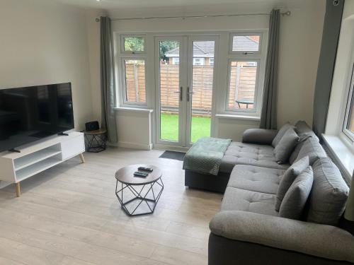 a living room with a couch and a flat screen tv at Rose Mews, Newly Refurbed Modern Interior with Garden in Edmonton