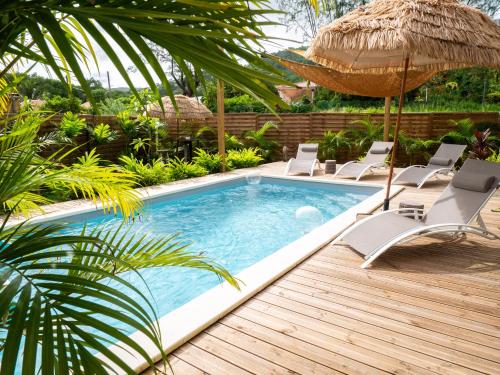 a swimming pool with chairs and an umbrella at Coco Soley in Le Diamant