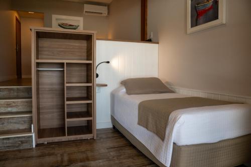a small bedroom with a bed and a closet at Hotel Atalaia do Mariscal in Bombinhas