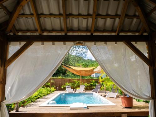 a swimming pool in a gazebo with white curtains at Coco Soley in Le Diamant