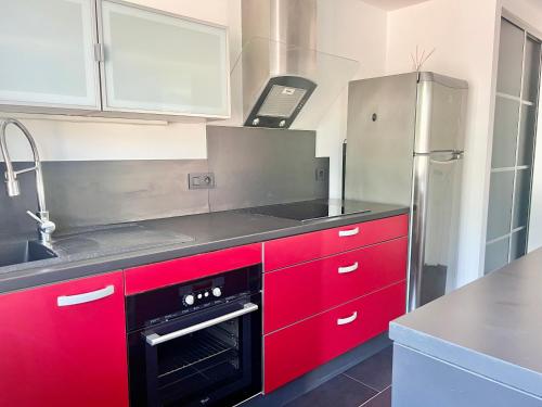 a kitchen with red cabinets and a black oven at Charmant T2 Sallanches in Sallanches