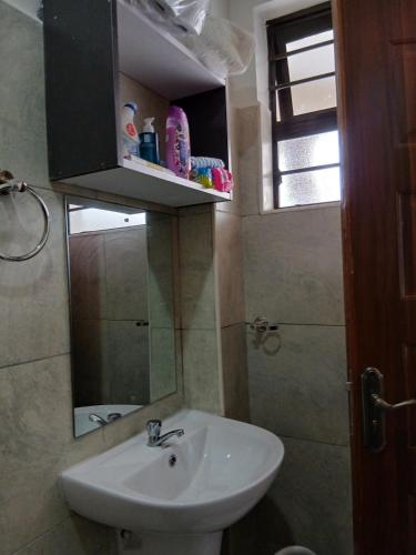 a bathroom with a sink and a mirror at A cozy spacious studio apartment with a balcony in Nairobi