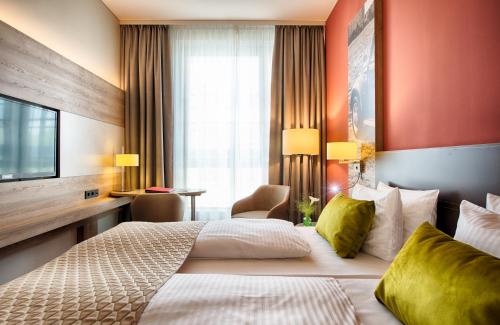 a hotel room with two beds and a television at Leonardo Hotel Wolfsburg City Center in Wolfsburg