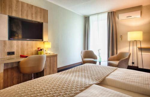 a hotel room with a bed and a flat screen tv at Leonardo Hotel Wolfsburg City Center in Wolfsburg