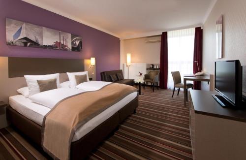 a hotel room with a large bed and a tv at Leonardo Hotel Wolfsburg City Center in Wolfsburg