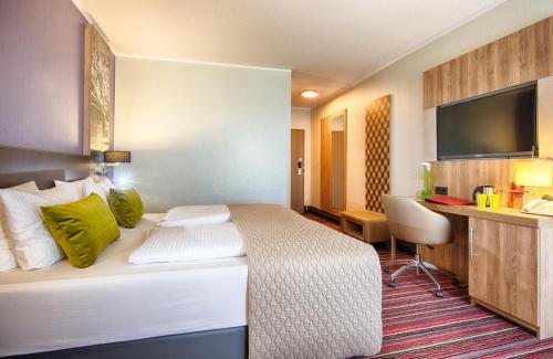 a hotel room with a bed and a desk at Leonardo Hotel Wolfsburg City Center in Wolfsburg