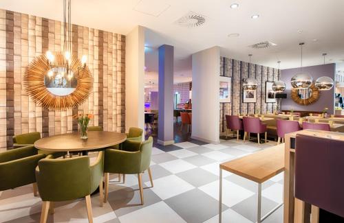 a restaurant with a dining room with tables and chairs at Leonardo Hotel Wolfsburg City Center in Wolfsburg