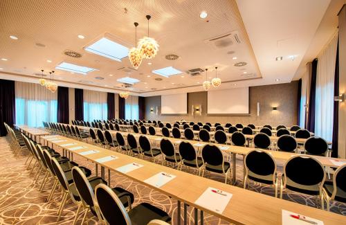 a conference room with rows of tables and chairs at Leonardo Hotel Wolfsburg City Center in Wolfsburg