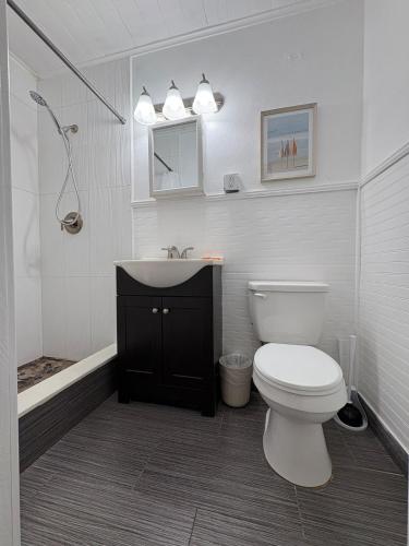 a bathroom with a toilet and a sink and a mirror at Stylish Coastal Studio Walk to Beach, Pool & Eats in Riviera Beach