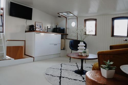 Una sala de estar con televisor, silla y mesa en City center Amstel river Houseboat Kom en Zie, en Ámsterdam