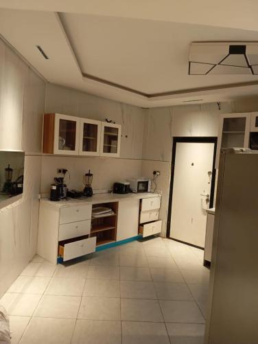 a large kitchen with white cabinets and a door at Sujimoto Shortlet Ave Forche, Banana Island, Ikoyi in Ikoyi