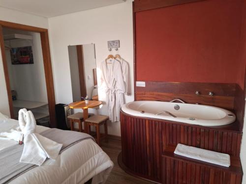 a bathroom with a bath tub next to a bed at Pousada Casa Pinha em Campos do Jordão in Campos do Jordão