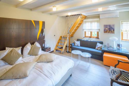 a bedroom with a bed and a couch and a staircase at Hotel - Restaurant Le Cerf & Spa in Marlenheim