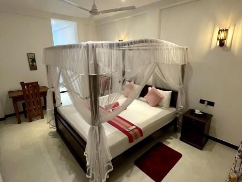 a bedroom with a canopy bed with pink pillows at Green nature in Mirissa